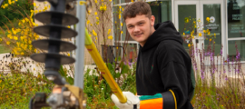 A high school student uses a long yellow stick to attach a mock electric fuse