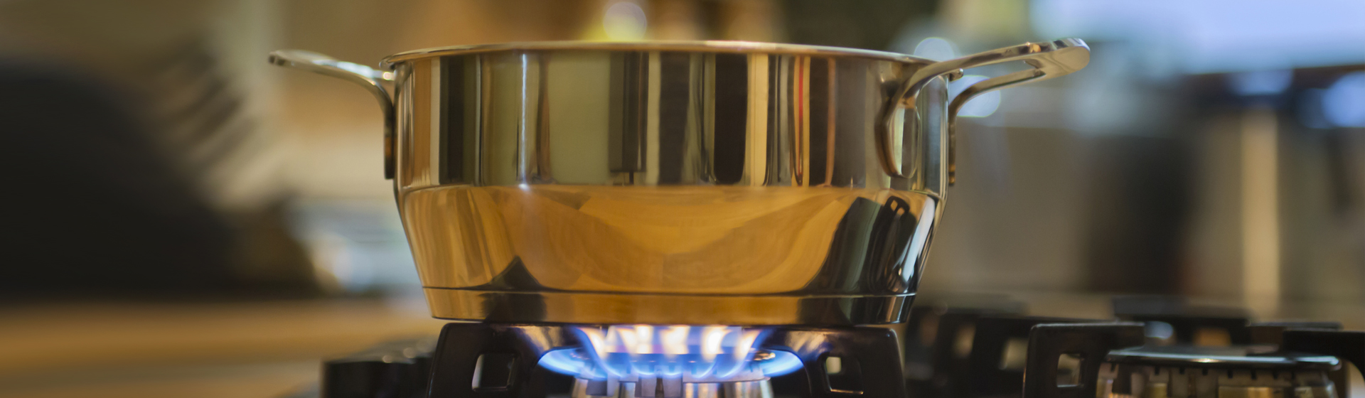 stainless steel saucepan on gas stove burner with a blue flame